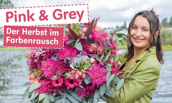 Frau haelt großen pink und graufarbigen Herbststrauss